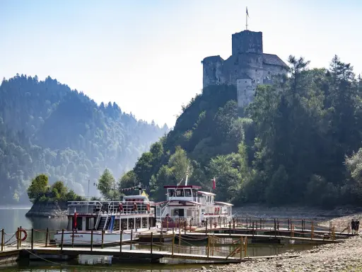Zamek na skale nad jeziorem, z zacumowanymi statkami wycieczkowymi. Niezapomniane atrakcje Małopolska.