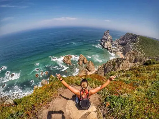 Frau genießt die atemberaubende Lissabon Natur am Cabo da Roca. Türkises Meer, Felsen und üppige Vegetation.