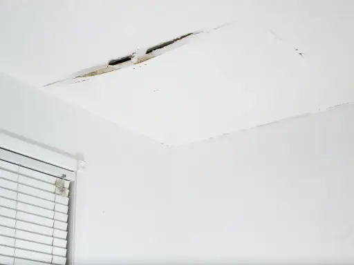 Widoczne pęknięcia na łączeniu sufitu i ściany, świadczące o problemach z konstrukcją lub wilgocią.