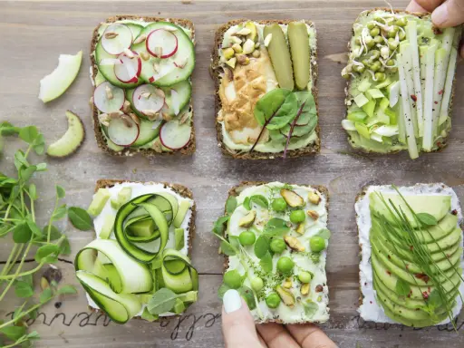 Sześć pysznych kanapek z awokado, ozdobionych warzywami, kiełkami i orzechami. Idealne na zdrowy lunch!