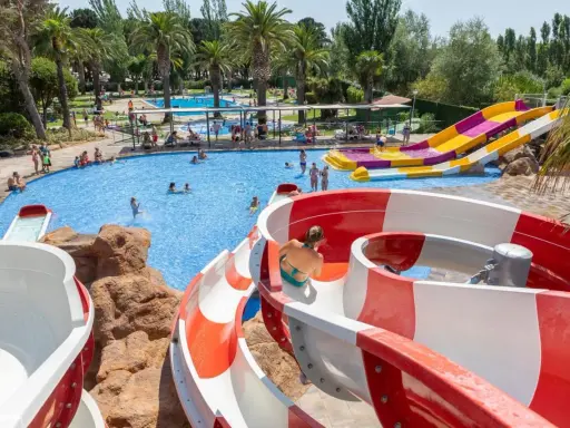 Disfruta de los mejores campings de Catalunya con piscinas y toboganes acuáticos. Familias se divierten en un día soleado.