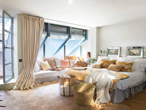 Habitación acogedora con cama grande, cojines coloridos y una zona de lectura junto a la ventana. Ideas para decorar habitacion con estilo natural.