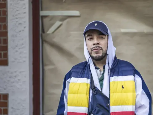 Man i hip hop style med keps och färgglad jacka.