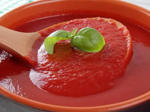 Gęsty, domowy ketchup w ceramicznej misie, nabierany drewnianą łyżką. Idealny przepis na ketchup z bazylią.
