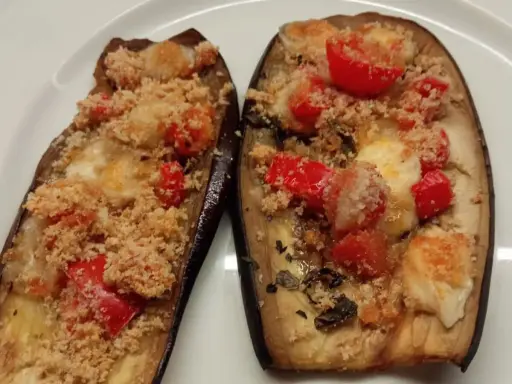 Melanzane ripiene al forno, con pomodorini, formaggio filante e pangrattato croccante. Un'ottima crema di melanzane.