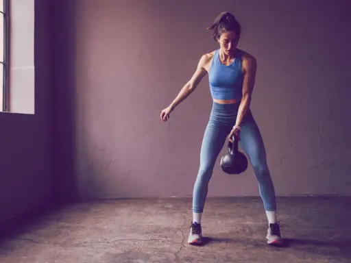 Frau trainiert mit Kettlebell, Teil der 75 Hard Challenge.