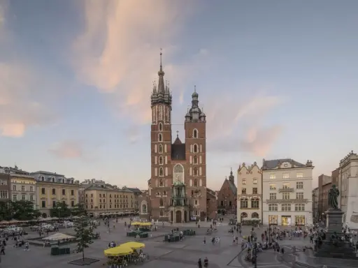 Majestatyczna Bazylika Mariacka góruje nad Rynkiem Głównym w Krakowie. Tłumy spacerują, podziwiając architekturę i atmosferę miasta.