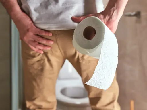 Mężczyzna w łazience trzymający rolkę papieru toaletowego. Zastanawia się, ile razy dziennie powinno się sikać.