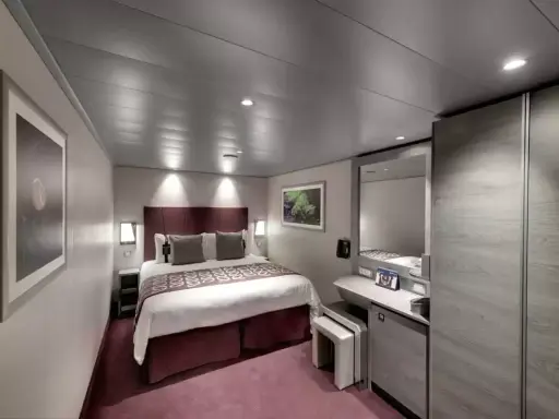Cabina MSC Seaside, ponte 14: letto matrimoniale, specchio, armadio e un quadro decorativo.