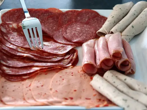 Talerz z wędlinami: salami, szynka, kiełbasa. Jak przechowywać wędlinę w lodówce? Najlepiej w szczelnym pojemniku.
