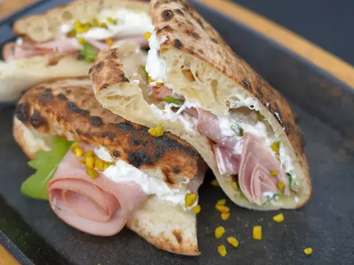 Gegrillte Pizza-Taschen gefüllt mit cremiger Ricotta, Mortadella und Pistazien.