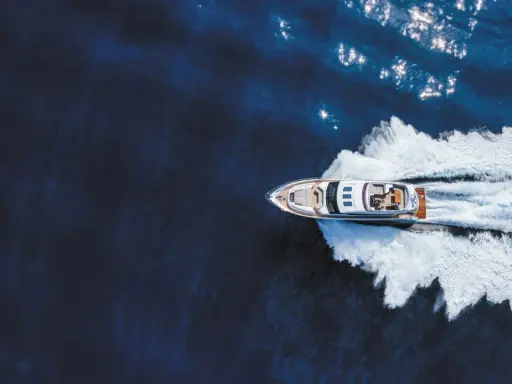 Un bateau hors-bord puissant fend les eaux bleues, laissant une traînée d'écume blanche derrière lui.