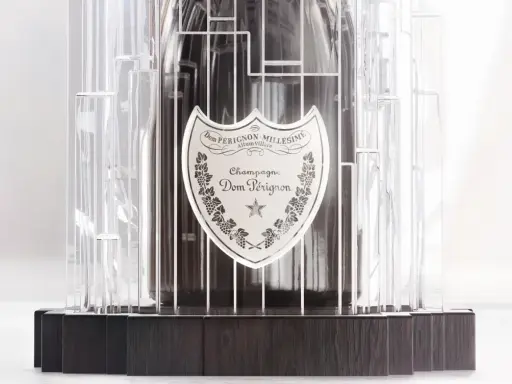Dom Pérignon Vintage 2012 in einer modernen, transparenten Hülle mit dunklem Holzsockel.