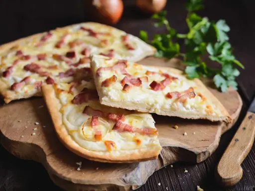 Flammekueche, une spécialité alsacienne d'origine, garnie de lardons et d'oignons sur une pâte fine.