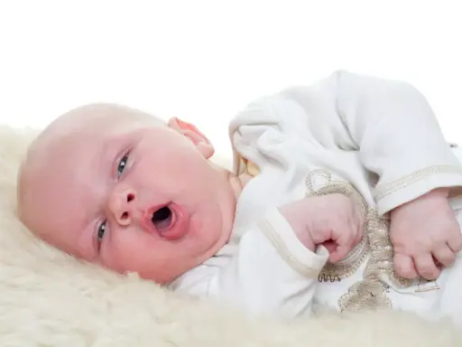 Baby mit offenem Mund, vielleicht husten. Was tun? Ein süßer kleiner Mensch auf weichem Fell.