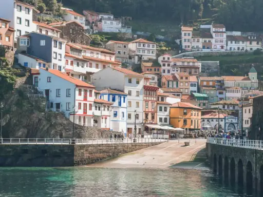 Casas de colores se aferran a la ladera en uno de los pueblos con encanto en Asturias, con el mar turquesa al frente.