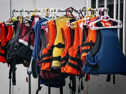 Chalecos salvavidas de varios colores, como naranja, amarillo y azul, colgados en perchas. Listos para la aventura, estos chalecos son de epis categoria 2.