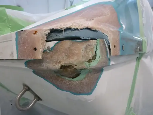 Beschädigte Stelle an einem GFK Boot, bereit für die Reparatur. Die Fasern sind freigelegt, ein Zeichen für notwendige Instandsetzung.