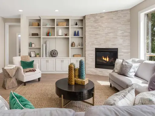 Un elegante mueble salones con chimenea de piedra, estanterías repletas de objetos decorativos y cómodos sofás.