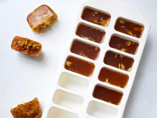 Eiswürfelbehälter mit gefrorener Brühe und Gewürzen. So kann man einfach Suppe einfrieren und später verwenden.