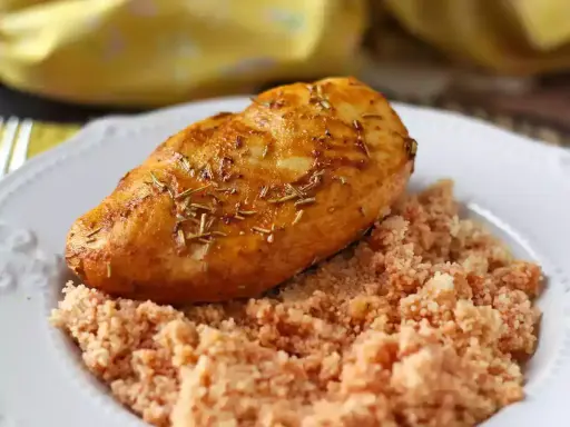 Petto di pollo in friggitrice ad aria, dorato e aromatico, servito su un letto di couscous.