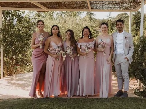 Grupo de damas de honor y el novio posando para una foto en una boda informal campo.