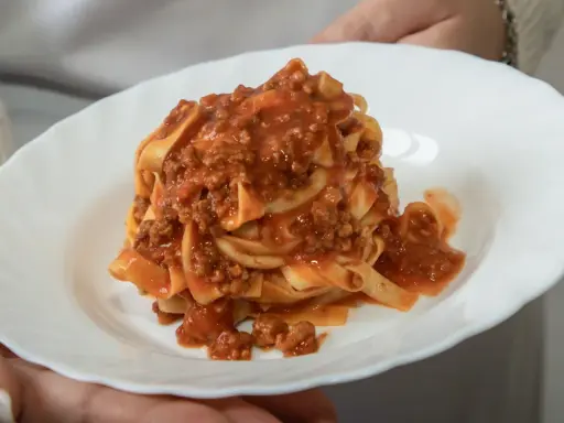 Un piatto di tagliatelle al ragù, un classico della cucina italiana, servito su un piatto bianco.