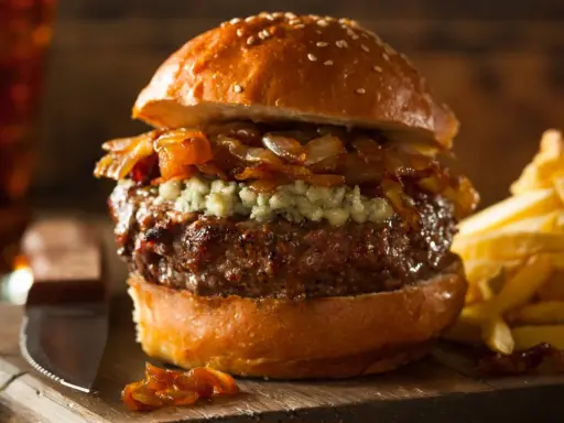 Jugosa hamburguesa con queso de cabra desmenuzado, cebolla caramelizada y papas fritas crujientes.