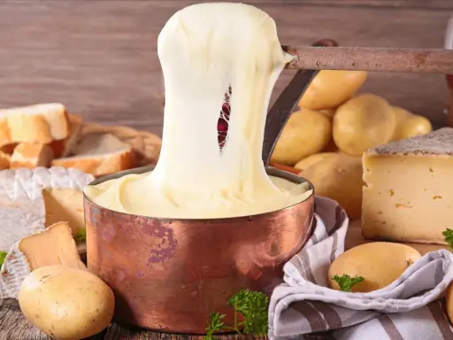 Fondue au fromage, un délice des spécialités culinaires auvergnates, avec du pain, des pommes de terre et du vin rouge.