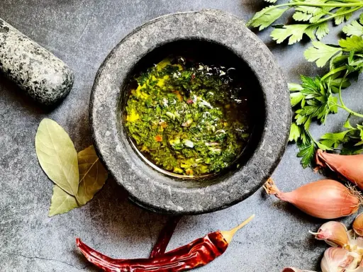 Frische Kräuter, Knoblauch, Schalotten und Chili – die chimichurri hauptzutaten werden im Mörser zubereitet.