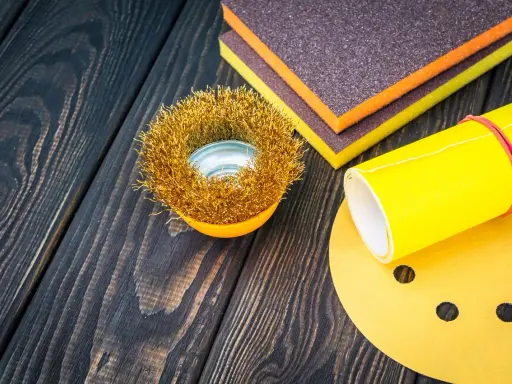 Outils de ponçage : brosse métallique, éponges abrasives et papier de verre pour préparer une surface en polyester avant l'application d'époxy.