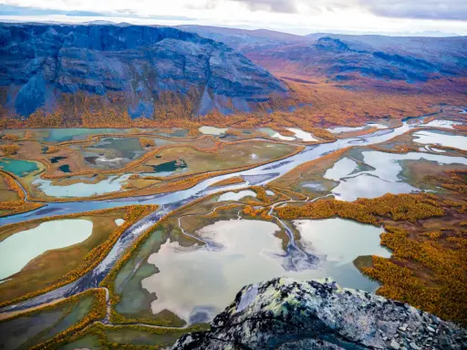 Vacker höstfärgad vy över Kungsleden, med slingrande vattendrag och fjäll. Perfekt tid att vandra.