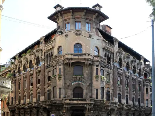 Dettagli architettonici unici del **Palazzo Galimberti Milano**, con balconi ornati e sculture che emergono dalla facciata.