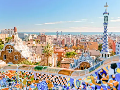 Kolorowe mozaiki i bajkowe budowle w Parku Güell z widokiem na Barcelonę.