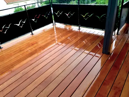 Terrasse privative en copropriété avec un plancher en bois brillant et des panneaux décorés de silhouettes d'oiseaux.
