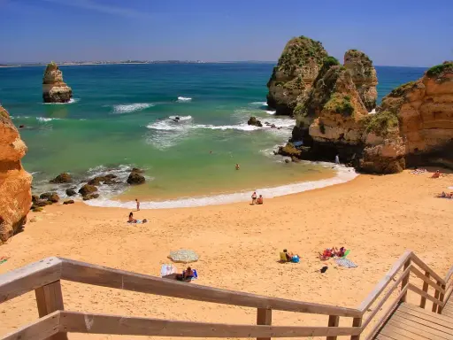 Sonnige Bucht mit goldenem Sand und Felsformationen. Ein perfekter Ort für einen entspannten Tag am Meer, nur eine kurze Fahrt vom Flughafen Portugal Algarve entfernt.