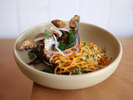 Poisson frit croustillant avec salade de carottes râpées et oignons rouges, une spécialité du restaurant la joie.