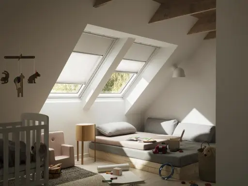 Habitación infantil con dos ventanas de tejado equipadas con cortinas para Velux caseras, cama baja, cuna y juguetes.