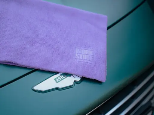 Fioletowa mikrofibra z logo Work Stuff na masce zielonego Aston Martina. Idealna do pielęgnacji auta.