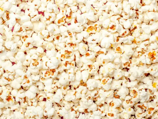 Mnóstwo puszystego popcornu, idealnego na wieczór filmowy. Czy pies może popcorn? Lepiej nie ryzykować, choć wygląda apetycznie!