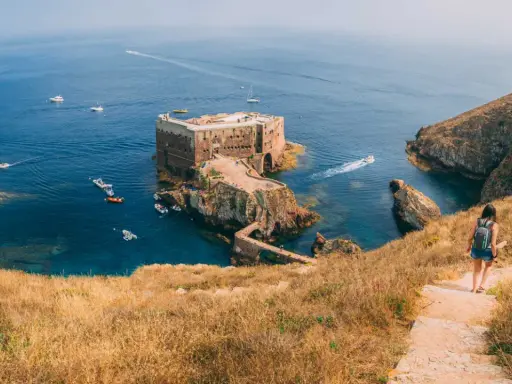 Wanderin auf der Insel Berlenga Grande, Portugal, Leiria. Eine Festung thront im Meer, Boote schaukeln im Wasser.