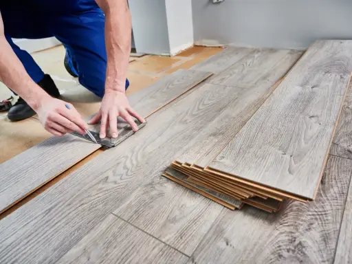 Handwerker misst Laminat für die Verlegung. Die Kosten für Laminat verlegen sind oft überschaubar.