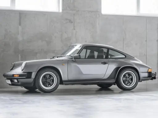 Grauer Porsche 911 G-Modell steht vor einer Betonwand.