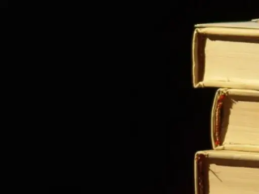 Libri impilati, un libro in cima con una matita. La luce crea ombre, un po' come l'anastrofe figura retorica che inverte l'ordine per enfasi.