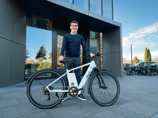 Mężczyzna w okularach stoi obok białego roweru elektrycznego marki Groclin.