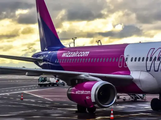Samolot Wizz Air na płycie lotniska pod pochmurnym niebem.