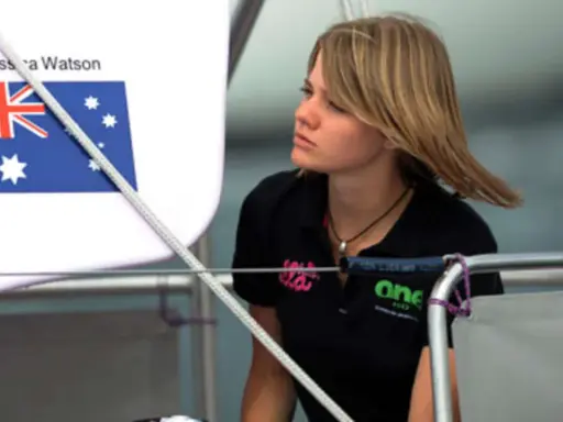Jessica Watson heute, blickt nachdenklich auf dem Boot. Die australische Flagge ist im Hintergrund zu sehen.