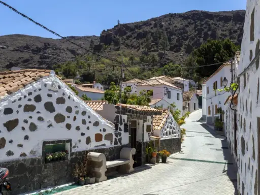 Urokliwa uliczka z białymi domami i kamiennymi zdobieniami na Gran Canarii. Odkryj te i inne **Gran Canaria atrakcje**!