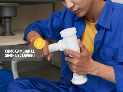 Un fontanero realiza la instalación del sifón del lavabo, sujetando la pieza blanca con ambas manos.