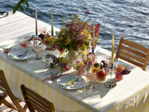 Enkel dukning vid vattnet med blommor och ljus.